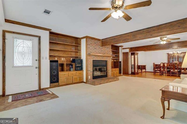 living room with beam ceiling, a brick fireplace, built in shelves, and ceiling fan with notable chandelier