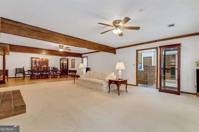 living room with beamed ceiling, ornamental molding, ceiling fan with notable chandelier, and light colored carpet