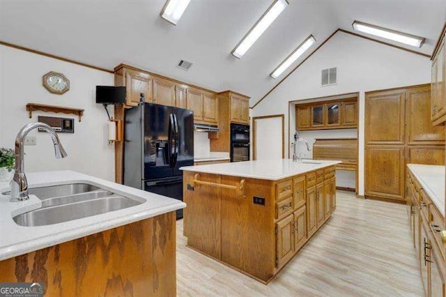 kitchen featuring sink, vaulted ceiling, black appliances, and a center island with sink