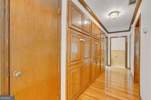 hallway featuring ornamental molding and light hardwood / wood-style floors