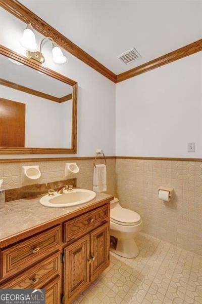 bathroom featuring tile walls, tile patterned flooring, vanity, toilet, and crown molding