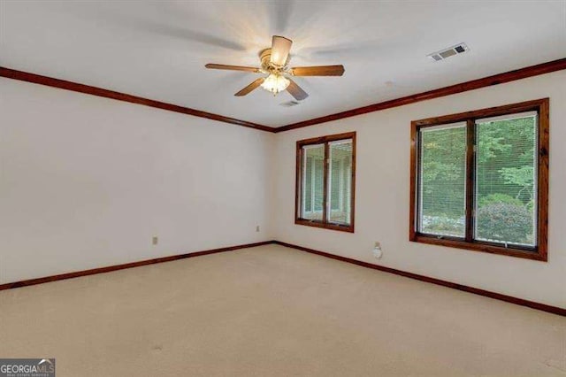 empty room featuring ceiling fan, ornamental molding, and light carpet