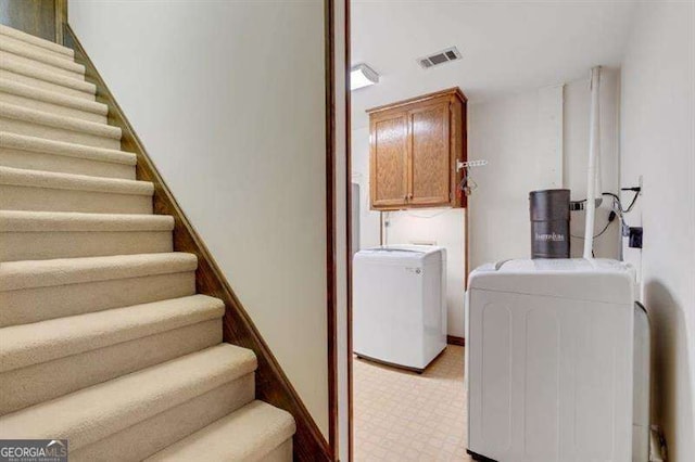 laundry room with washing machine and dryer and cabinets