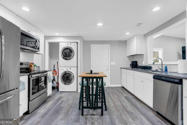 kitchen with stacked washer and dryer, sink, white cabinets, and appliances with stainless steel finishes