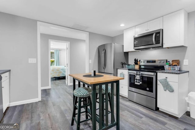 kitchen with stainless steel appliances, hardwood / wood-style floors, and white cabinets