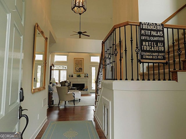 staircase featuring wood-type flooring, ceiling fan, and a high ceiling