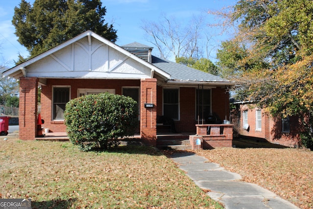 bungalow-style home with a front yard and covered porch