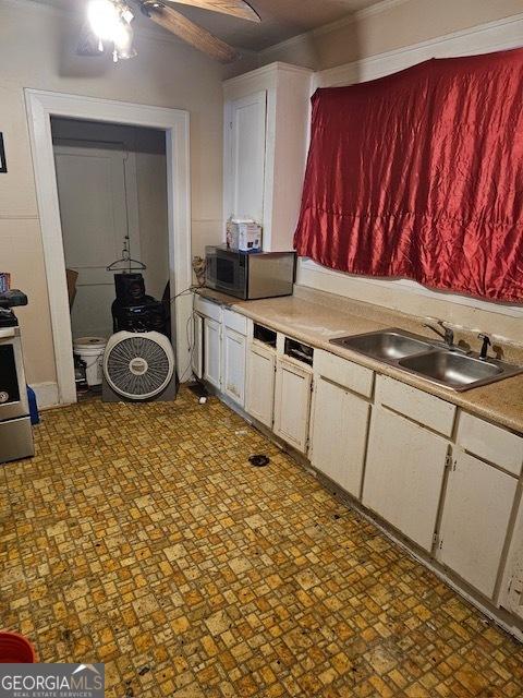 kitchen with stainless steel electric range oven, white cabinetry, sink, and ceiling fan