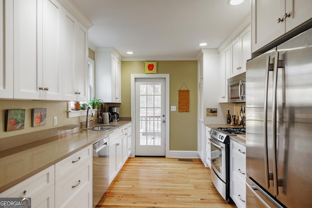 kitchen featuring stainless steel appliances, white cabinetry, sink, and light hardwood / wood-style floors