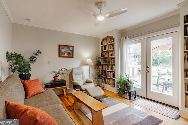 living room featuring built in shelves, french doors, crown molding, light hardwood / wood-style flooring, and ceiling fan