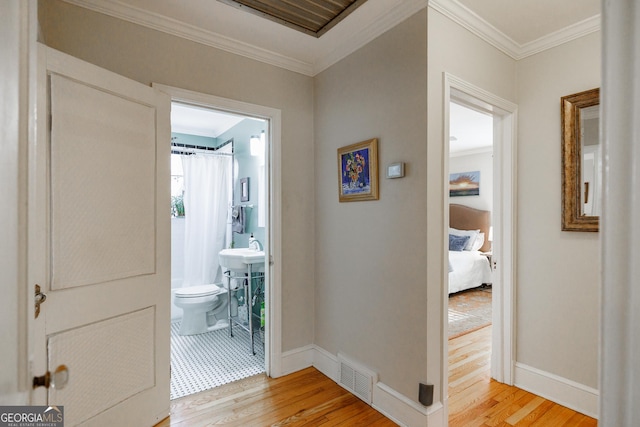 corridor with hardwood / wood-style floors and crown molding