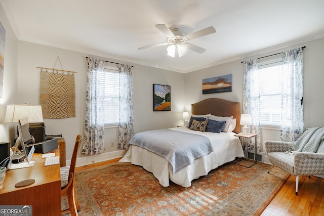 bedroom featuring hardwood / wood-style flooring, ornamental molding, ceiling fan, and multiple windows