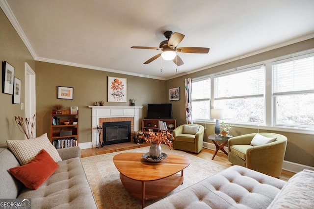 living room featuring a brick fireplace, crown molding, light hardwood / wood-style flooring, and ceiling fan