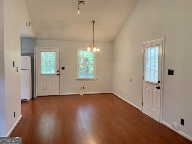 entrance foyer with vaulted ceiling, dark hardwood / wood-style floors, and a notable chandelier