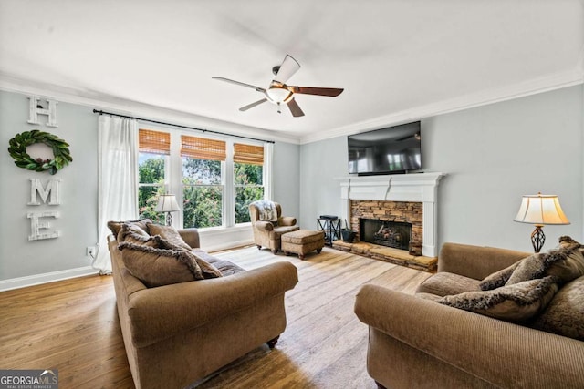 living room featuring hardwood / wood-style floors, crown molding, a fireplace, and ceiling fan