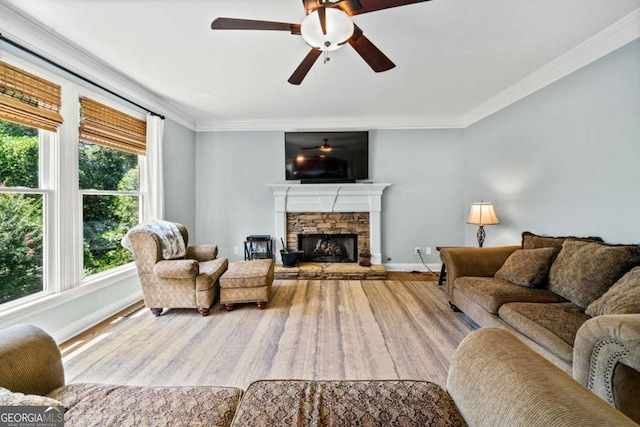 living room with ornamental molding, a stone fireplace, hardwood / wood-style floors, and ceiling fan