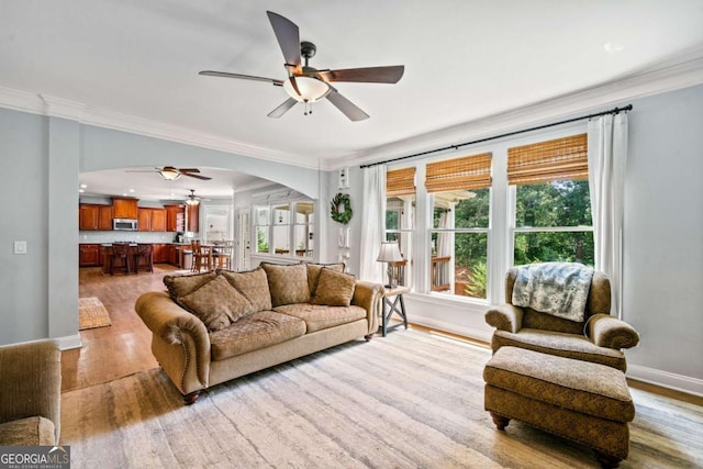 living room featuring light hardwood / wood-style flooring, ornamental molding, and ceiling fan