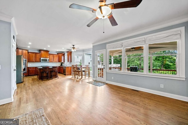 living room with light hardwood / wood-style flooring, ornamental molding, and ceiling fan