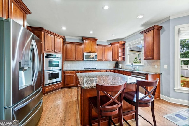 kitchen featuring light stone countertops, stainless steel appliances, a breakfast bar, and a kitchen island