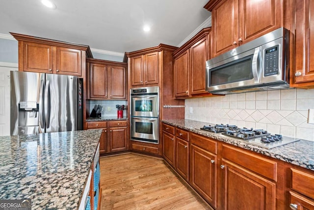 kitchen with tasteful backsplash, appliances with stainless steel finishes, light hardwood / wood-style floors, and dark stone counters