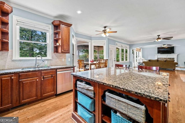 kitchen featuring light stone counters, stainless steel dishwasher, sink, and tasteful backsplash