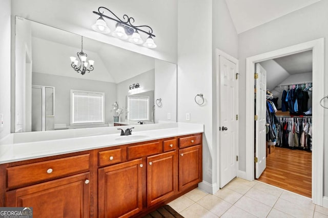 bathroom with vaulted ceiling, a shower with shower door, vanity, tile patterned floors, and an inviting chandelier