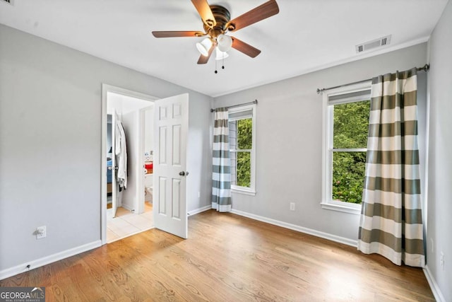 unfurnished bedroom with ensuite bathroom, ceiling fan, and light hardwood / wood-style floors