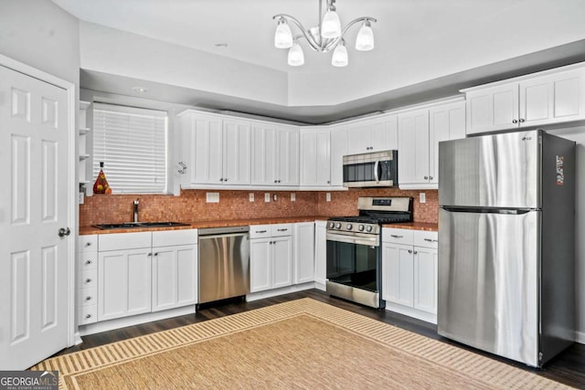 kitchen featuring white cabinetry, sink, decorative light fixtures, and appliances with stainless steel finishes