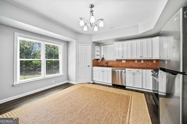 kitchen with pendant lighting, sink, dark wood-type flooring, stainless steel appliances, and white cabinets