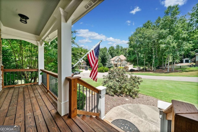 wooden deck featuring a lawn and covered porch