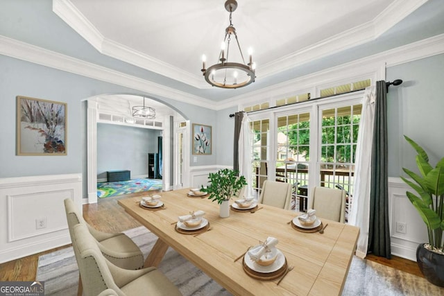 dining room featuring hardwood / wood-style floors, a tray ceiling, ornamental molding, and a chandelier