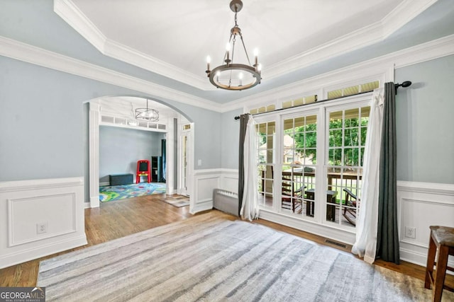 living room with a notable chandelier, a tray ceiling, ornamental molding, and hardwood / wood-style floors