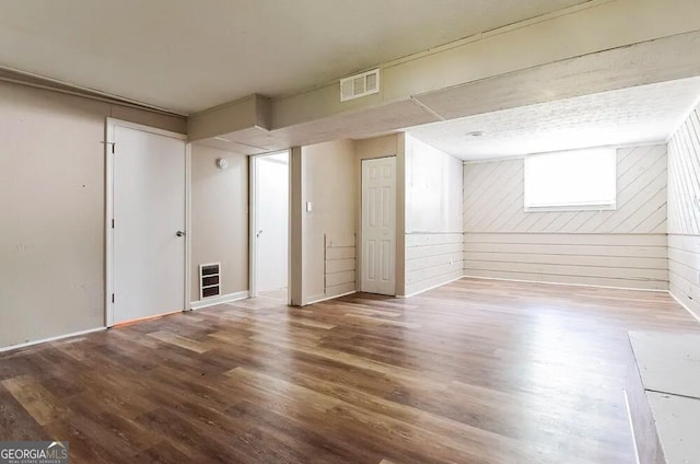 basement with hardwood / wood-style flooring and wooden walls