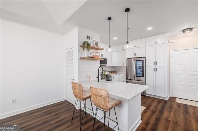 kitchen featuring appliances with stainless steel finishes, hanging light fixtures, white cabinets, vaulted ceiling, and kitchen peninsula