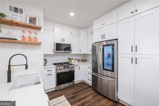 kitchen featuring sink, white cabinetry, dark hardwood / wood-style floors, stainless steel appliances, and backsplash