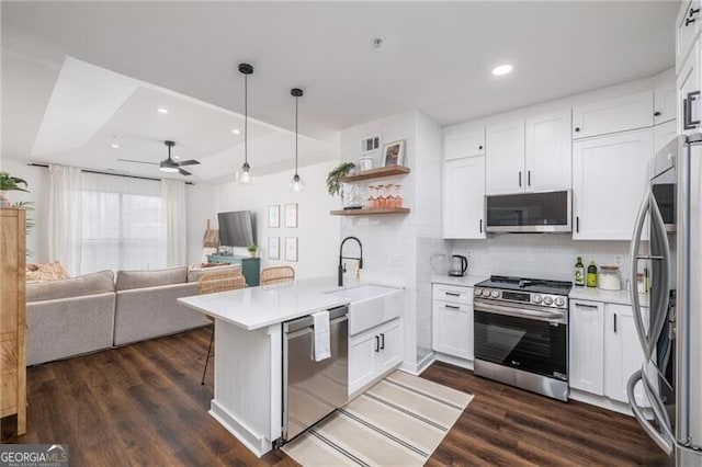 kitchen with pendant lighting, sink, white cabinets, kitchen peninsula, and stainless steel appliances