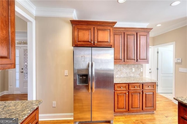 kitchen featuring crown molding, stainless steel fridge with ice dispenser, light wood-type flooring, light stone countertops, and decorative backsplash