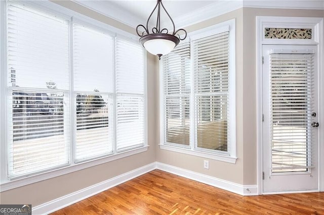 unfurnished dining area with wood-type flooring, a wealth of natural light, and crown molding