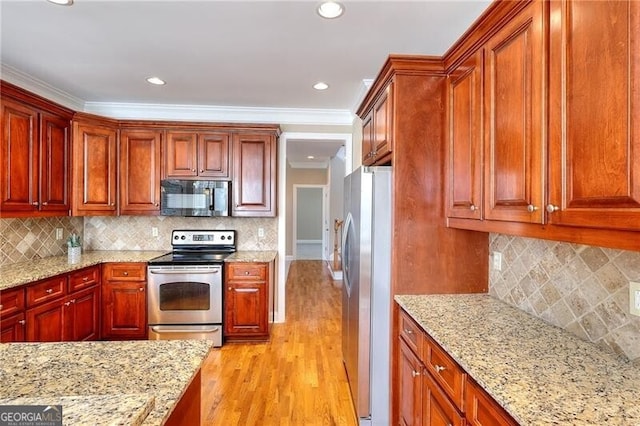 kitchen with stainless steel appliances, ornamental molding, light stone countertops, and decorative backsplash