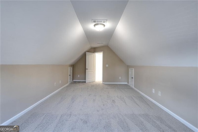 bonus room with lofted ceiling and light carpet