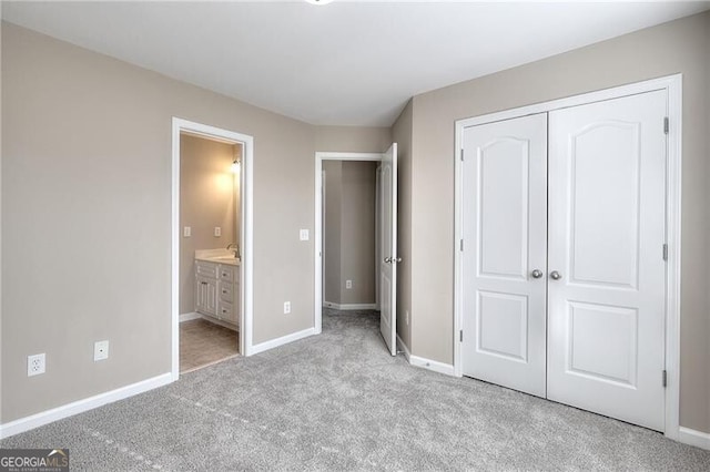 unfurnished bedroom featuring ensuite bathroom, light carpet, and a closet