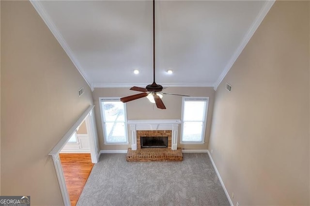 unfurnished living room featuring light carpet, a brick fireplace, ornamental molding, and ceiling fan