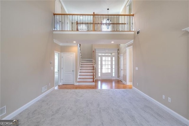 carpeted foyer entrance with crown molding and a towering ceiling