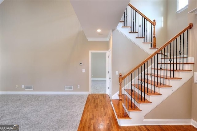 staircase featuring ornamental molding and hardwood / wood-style floors