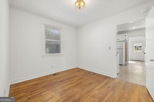 empty room featuring ornamental molding and light wood-type flooring