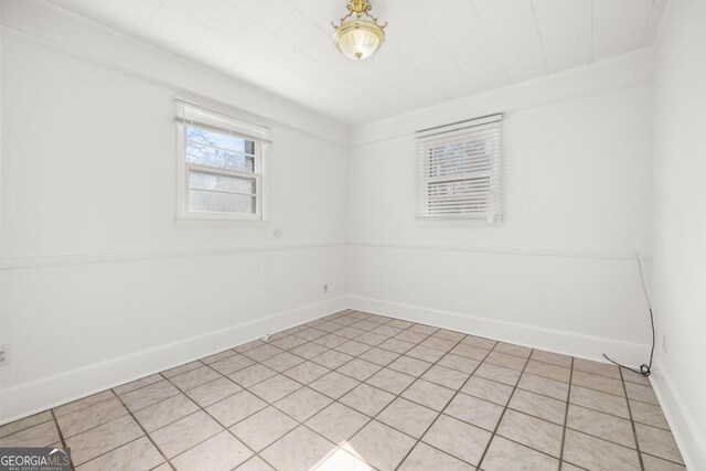 unfurnished room with light tile patterned floors and crown molding