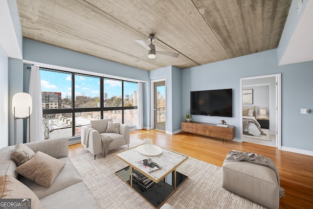 living room with wood finished floors, a ceiling fan, and baseboards