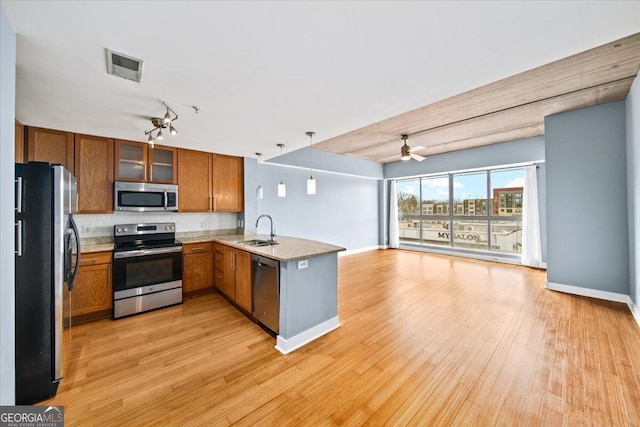 kitchen featuring a peninsula, a sink, visible vents, open floor plan, and appliances with stainless steel finishes