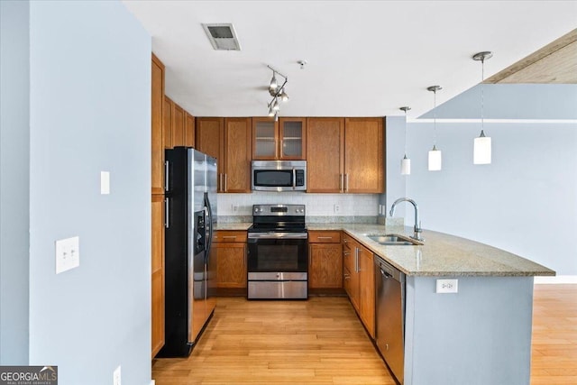 kitchen with a peninsula, appliances with stainless steel finishes, visible vents, and brown cabinets