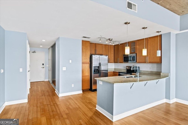 kitchen featuring visible vents, light wood-style flooring, brown cabinets, a peninsula, and stainless steel appliances